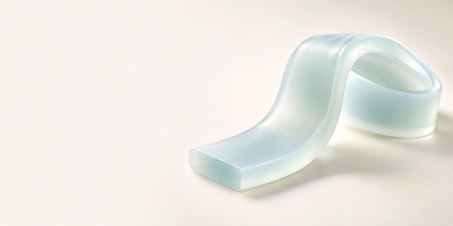 Softly bent translucent pale-aqua silicone with rounded thick edges